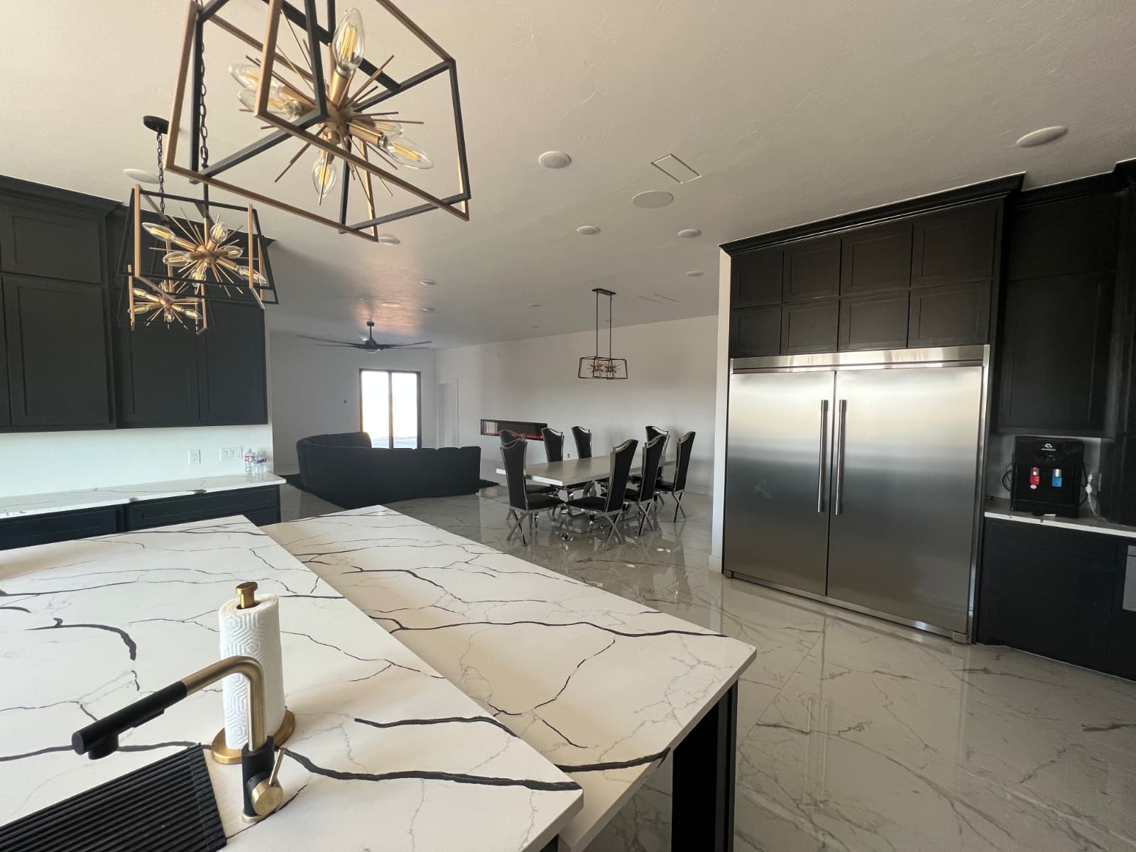 Dark cabinet kitchen with marble countertops and starburst chandeliers