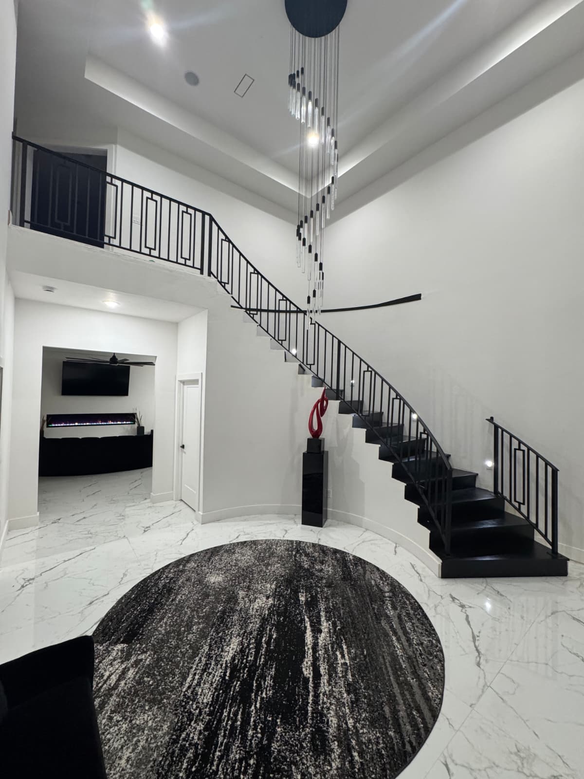Grand two-story foyer with iron staircase and modern chandelier